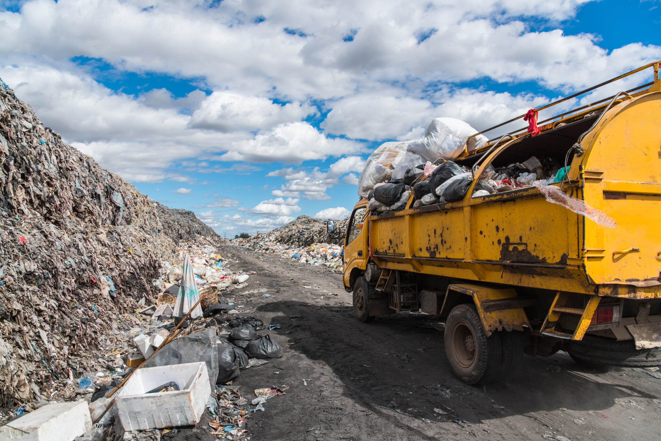 Dump trucks unloading garbage over vast landfill.