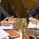 Two experienced lawyers in formalwear interacting by workplace